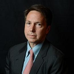 Person wearing suit standing in front of dark wall