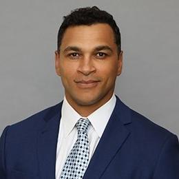 Person wearing navy suit in front of grey background